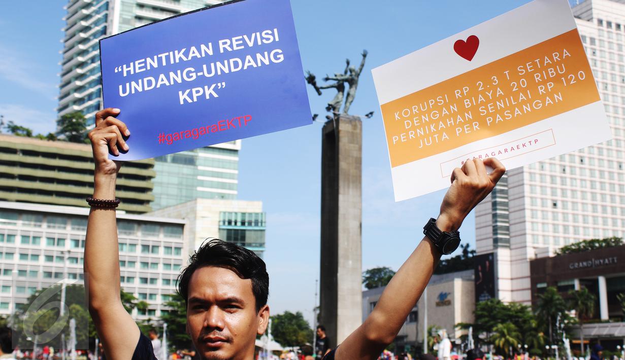 Seorang pria membawa poster saat aksi di CFD, Jakarta, Minggu (19/3). Aktivis Gerakan Sapu Koruptor meminta kepada pemerintah untuk menghentikan Revisi Undang-undang KPK. (Liputan6.com/Angga Yuniar) 