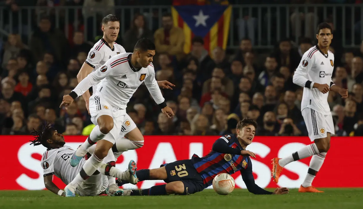 Pemain Barcelona, Gavi (dua kanan) dijaga ketat dua pemain Manchester United, Fred dan Casemiro dalam pertandingan leg pertama play-off fase knockout Liga Europa 2022/2023 yang digelar di Stadion Spotify Camp Nou, Jumat (17/2/2023) dini hari WIB. (AP Photo/Joan Monfort)