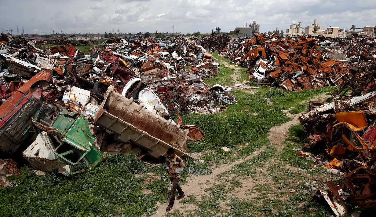 Seorang pria berjalan di tanah lapang yang berisi kendaraan yang rusak, di Mosul Barat, Irak, 3 April 2017. (AFP Photo/Ahmad Gharabli)