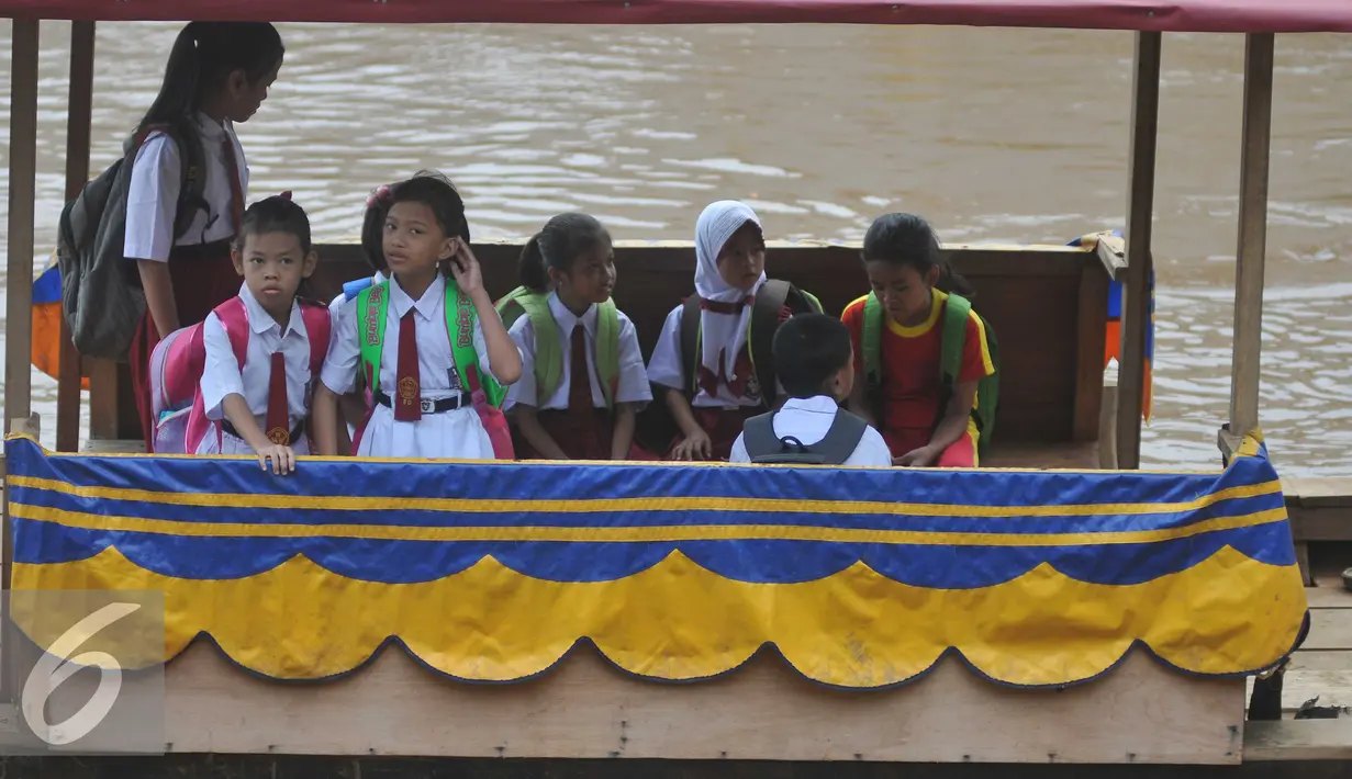 Sejumlah siswa SD menyeberangi sungai dengan perahu eretan untuk berangkat ke sekolah di Sungai Ciliwung, Jakarta, Senin, (4/1). Usai libur panjang para siswa kembali beraktivitas mengikuti tahun ajaran 2016-2017. (Liputan6.com/Gempur M Surya)