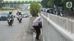Warga menerobos celah pagar pembatas jalan di depan Stasiun Pasar Minggu, Jakarta, Rabu (16/10/2019). Jauhnya jembatan penyeberangan orang (JPO) membuat warga memanfaatkan celah pagar pembatas tersebut sebagai akses menyeberang, meski berbahaya bagi keselamatan. (Liputan6.com/Immanuel Antonius)