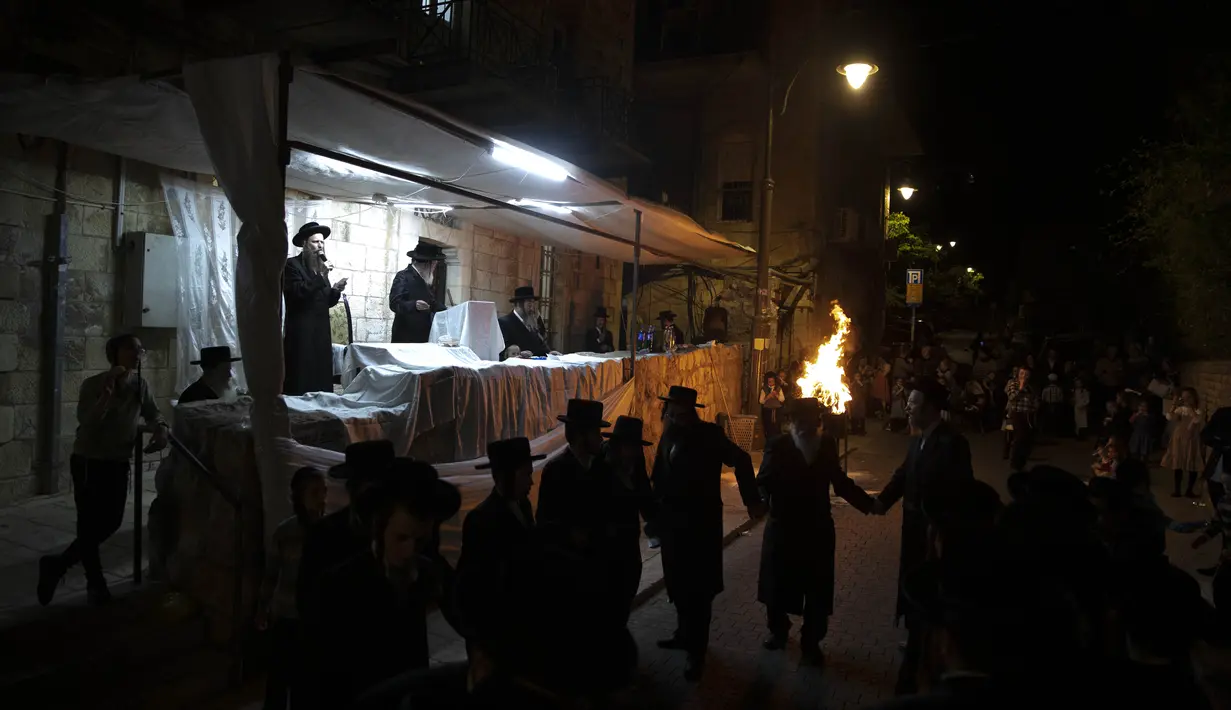 Yahudi Ultra-Ortodoks menari  di samping api unggun selama hari libur Yahudi perayaan Lag Ba'Omer di Bnei Brak, Israel, Kamis (29/4/2021). Liburan Lag Ba'Omer, menandai berakhirnya wabah yang dikatakan telah membinasakan orang Yahudi selama zaman Romawi. (AP Photo/Sebastian Scheiner)