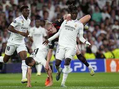 Pemain Manchester City, Erling Haaland (kanan kedua) terjatuh saat berebut bola dengan pemain Real Madrid, Eduardo Camavinga (kanan) dan Nacho pada laga leg pertama semifinal Liga Champions 2022/2023 di Santiago Bernabeu, Madrid, Rabu (10/05/2023) WIB. Laga berakhir dengan skor 1-1. (AP Photo/Manu Fernandez)