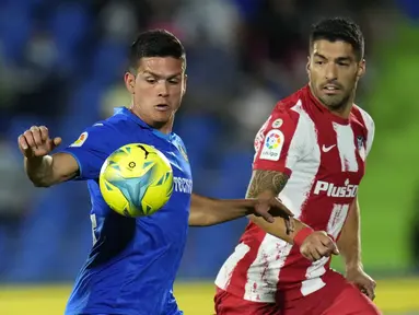 Bek Getafe, Jonathan Silva berebut bola dengan penyerang Atletico Madrid, Luis Suarez pada laga pekan keenam Liga Spanyol di Stadion Coliseum Alfonso Perez, Rabu (22/9/2021) dini hari WIB. Luis Suarez memborong dua gol saat Atletico Madrid mengalahkan Getafe 2-1. (AP Photo/Manu Fernandez)