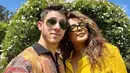 <p>Pasangan Nick Jonas dan Priyanka Chopra merayakan Paskah dengan outfit bernuansa kuning. Priyanka memilih kemeja kuning polos, sedangkan Nick Jonas mengenakan sweater rajut berkerah dengan motif abstrak. Keduanya berpose selfie di depan dekorasi taman berbentuk telinga kelinci yang gemas. Foto: Instagram.</p>