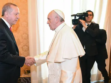 Presiden Turki Recep Tayyip Erdogan (kiri) bersalaman dengan Paus Fransiskus saat kunjungannya ke Vatikan (5/2). Erdogan menjadi Presiden Turki pertama selama 59 tahun yang mengunjungi Paus Fransiskus di Vatikan. (Alessandro Di Meo / Pool via AP)
