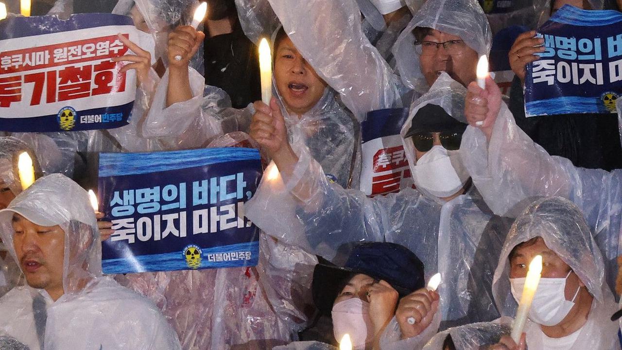 Mereka meneriakkan slogan-slogan saat menyalakan lilin menentang rencana Jepang untuk membuang air limbah olahan dari pembangkit listrik tenaga nuklir Fukushima ke laut, di Majelis Nasional di Seoul.