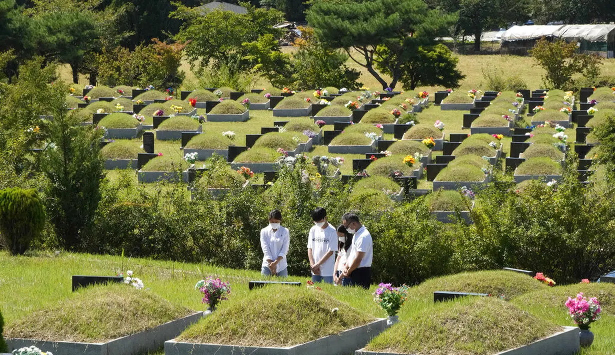 Anggota keluarga yang mengenakan masker memberi penghormatan kepada pemakaman leluhur mereka menjelang liburan Chuseok, Hari Thanksgiving versi Korea, di sebuah pemakaman di Paju, Korea Selatan, Minggu (12/9/2021).  (AP Photo/Ahn Young-joon)