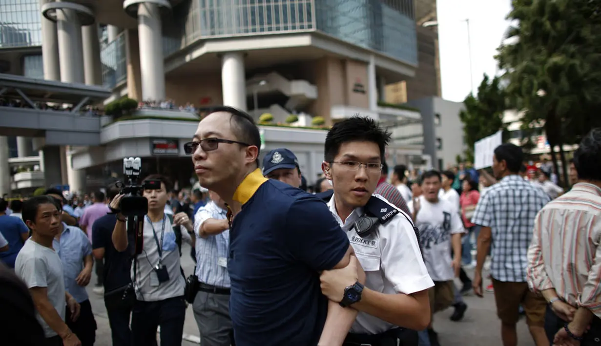 Salah satu anggota kelompok anti-demokrasi diamankan petugas kepolisian setempat dari lokasi utama berlangsungnya aksi demonstasi massa pro-demokrasi di Admiralty, Hong Kong, (13/10/2014). (REUTERS/Carlos Barria)
