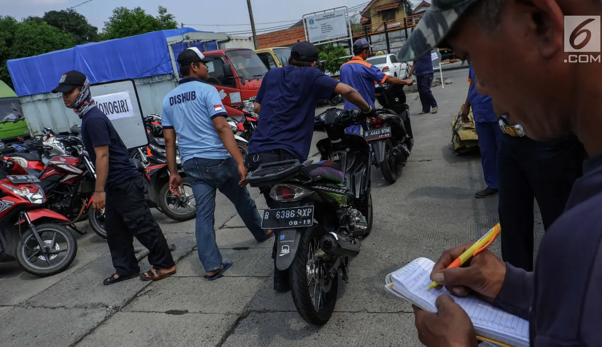 Petugas menaikkan sepeda motor milik peserta program mudik gratis dari Pemprov DKI Jakarta ke atas truk sebelum diberangkatkan di Terminal Pulogadung, Rabu (29/5/2019). Sebanyak 712 motor akan di kirim ke 10 kota tujuan pada tahap pertama Mudik Gratis Pemprov DKI 2019. (Liputan6.com/Faizal Fanani)