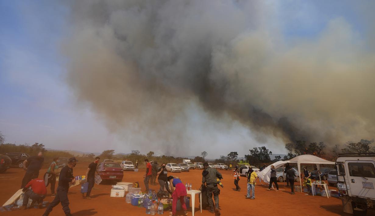 Petugas kepolisian, petugas pemadam kebakaran, dan sukarelawan membawa makanan dan air ke base camp mereka saat api menghanguskan sebagian Taman Juquery di Franco da Rocha, wilayah Sao Paulo, Brasil, Senin (23/8/2021). (AP/Andre Penner)