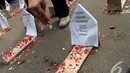Para pendemo menaburkan bunga pada nisan-nisan yang mereka letakkan di jalan raya. Aksi ini sebagai sindiran kepada pemerintah yang tak kunjung menuntaskan kasus tragedi 98, Jakarta, Selasa (24/06/2014) (Liputan6.com/Faisal R Syam)