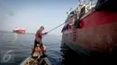 Supardi mengaitkan pengait untuk menahan kapal dari terjangan ombak  di perairan pesisir Cilincing, Jakarta, Jumat (17/3). (Liputan6.com/Faizal Fanani)