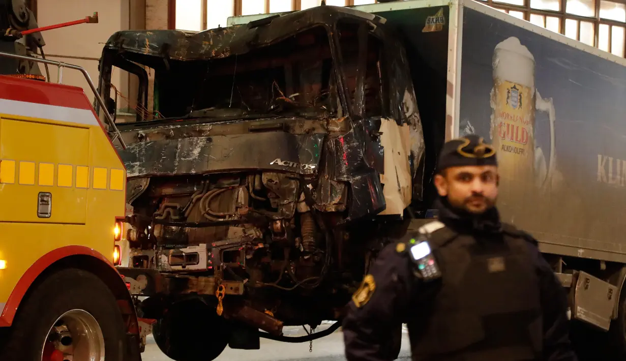 Petugas keamanan setempat berjaga di dekat truk yang menabrak kerumunan orang di Jalan Drottninggatan, pusat kota Stockholm, Swedia (8/4). (AP Photo / Markus Schreiber)
