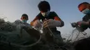 Nelayan Palestina mengenakan masker saat mereka melepaskan kepiting dari jaring di pantai laut Mediterania di Beit Lahyia, Jalur Gaza utara pada 21 September 2020. (AP Photo / Hatem Moussa)