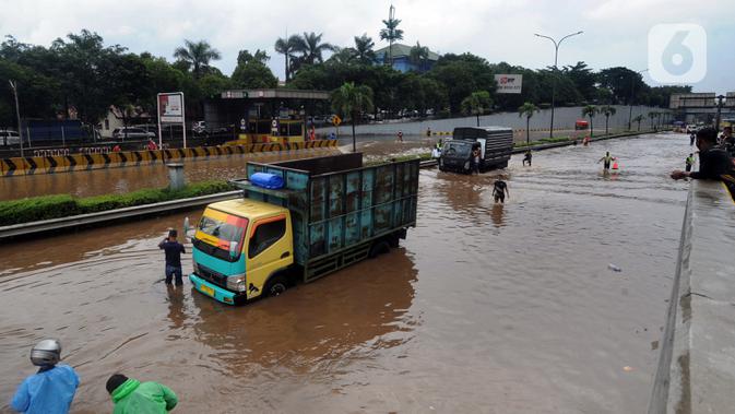 Sebuah truk mogok saat melintasi banjir yang menggenangi Jalan Tol JORR di kawasan TB Simatupang, Jakarta Selatan, Sabtu (20/2/2021). Banjir terjadi akibat luapan Kali Serua yang berada di pinggir jalan tol. (merdeka.com/Arie Basuki)