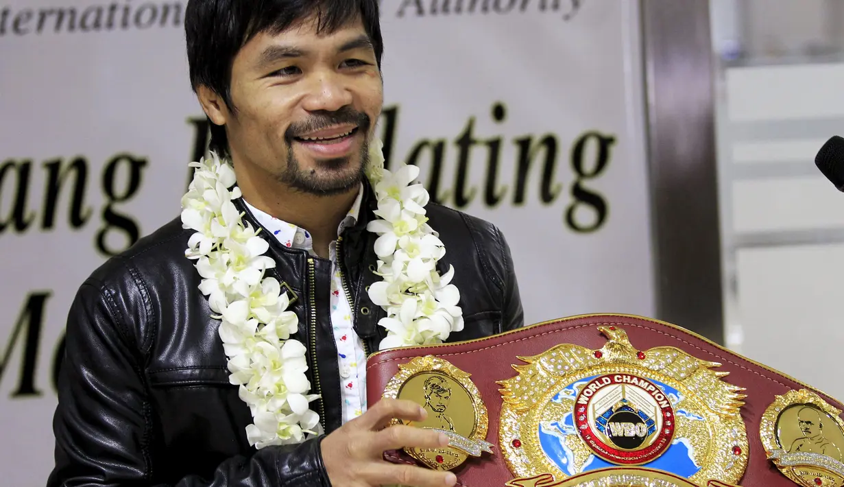 Petinju asal Filipina, Manny Pacquiao tersenyum sambil menunjukkan sabuk WBO kepada awak media usai mengalahkan Timothy Bradley setibanya di Bandara Internasional Ninoy Aquino, Manila (14/4). (REUTERS/Romeo Ranoco)