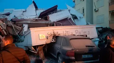 Sebuah mobil tetrimpa puing bangunan hotel yang rusak setelah gempa bumi di Durres,  Albania barat, Selasa (26/11/2019). Gempa bumi bermagnitudo 6,4 mengguncang Albania, Selasa dini hari yang menyebabkan beberapa bangunan dan gedung permukiman runtuh. (AP Photo)