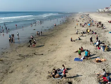 Pemandangan udara dari orang-orang di pantai di Playas de Tijuana dekat perbatasan AS-Meksiko di Tijuana, negara bagian Baja California, Meksiko, Sabtu (3/10/2020). Akhir pekan ini pantai di Playas de Tijuana dibuka kembali setelah ditutup sejak Maret lalu akibat Covid-19. (Guillermo Arias/AFP)