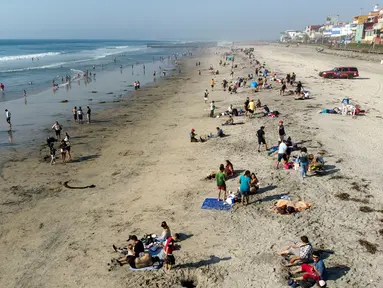 Pemandangan udara dari orang-orang di pantai di Playas de Tijuana dekat perbatasan AS-Meksiko di Tijuana, negara bagian Baja California, Meksiko, Sabtu (3/10/2020). Akhir pekan ini pantai di Playas de Tijuana dibuka kembali setelah ditutup sejak Maret lalu akibat Covid-19. (Guillermo Arias/AFP)