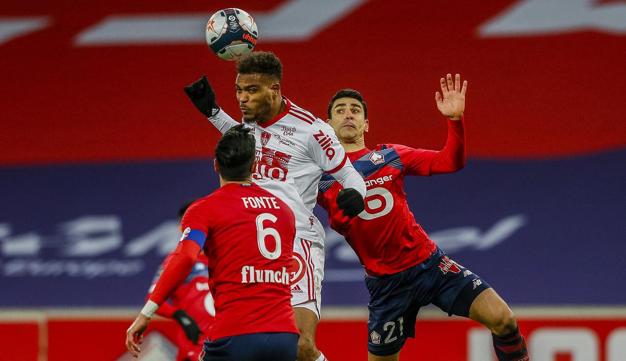 Striker Brest, Steve Mounie (tengah) melompat di antara dua pemain Lille, Jose Fonte (kiri) dan Benjamin Andre dalam laga lanjutan Liga Prancis 2020/21 pekan ke-25 di The Stade Pierre Mauroy, Lille, Minggu (14/2/2021). Brest bermain imbang 0-0 dengan Lille. (AP/Michel Spingler)