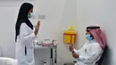 Seorang perawat berbicara kepada seorang pria sebelum memberikan vaksin Covid-19 di pusat vaksinasi yang diawasi Kementerian Kesehatan Arab Saudi di Riyadh, Arab Saudi, Kamis (17/12/2020). Berdasarkan informasi, proses vaksinasi di Arab Saudi akan dilakukan dalam tiga tahap.  (AFP/Fayez Nureldine)