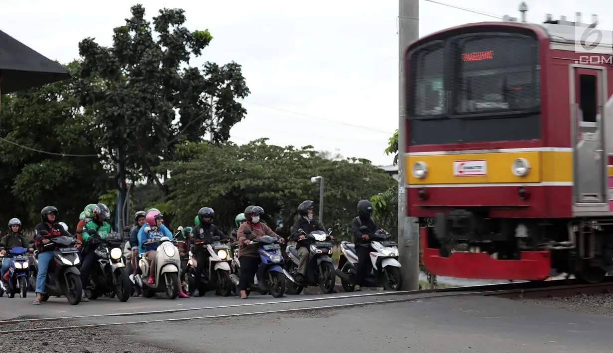 Pengendara sepeda motor menghentikan kendaraannya saat sebuah kereta api melintas di perlintasan kereta api tanpa palang pintu di kawasan Kelingkit, Rawa Buaya, Jakarta Barat, Selasa (26/2). (Liputan6.com/Johan Tallo)
