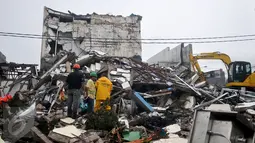 Alat berat membongkar reruntuhan bangunan PHD untuk mempermudah petugas Kepolisian melakukan proses olah TKP, Kota Bekasi, Minggu (23/10). Polisi akan melakukan olah TKP untuk memastikan penyebab ledakan tersebut. (Liputan6.com/Yoppy Renato)
