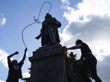 Mike Forcia (kiri) dan seorang pria mengikatkan tali pada leher patung Christopher Columbus saat sekelompok massa merobohkannya di Minnesota State Capitol, St. Paul, Minnesota, Amerika Serikat, Rabu (10/6/2020). (Evan Frost/Minnesota Public Radio via AP)