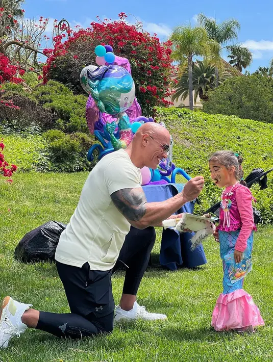 Aktor Dwayne Johnson alias The Rock bergaya sporty dengan legging saat menyuapi sang putri yang memakai kostum putri duyung (Foto: Instagram @therock)