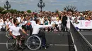 Presiden Prancis Emmanuel Macron didampingi petenis tenis Prancis, Michael Jeremias (belakang) bermain tenis diatas kursi roda di Paris, Prancis (24/6). (AFP Photo/Alain Jocard)