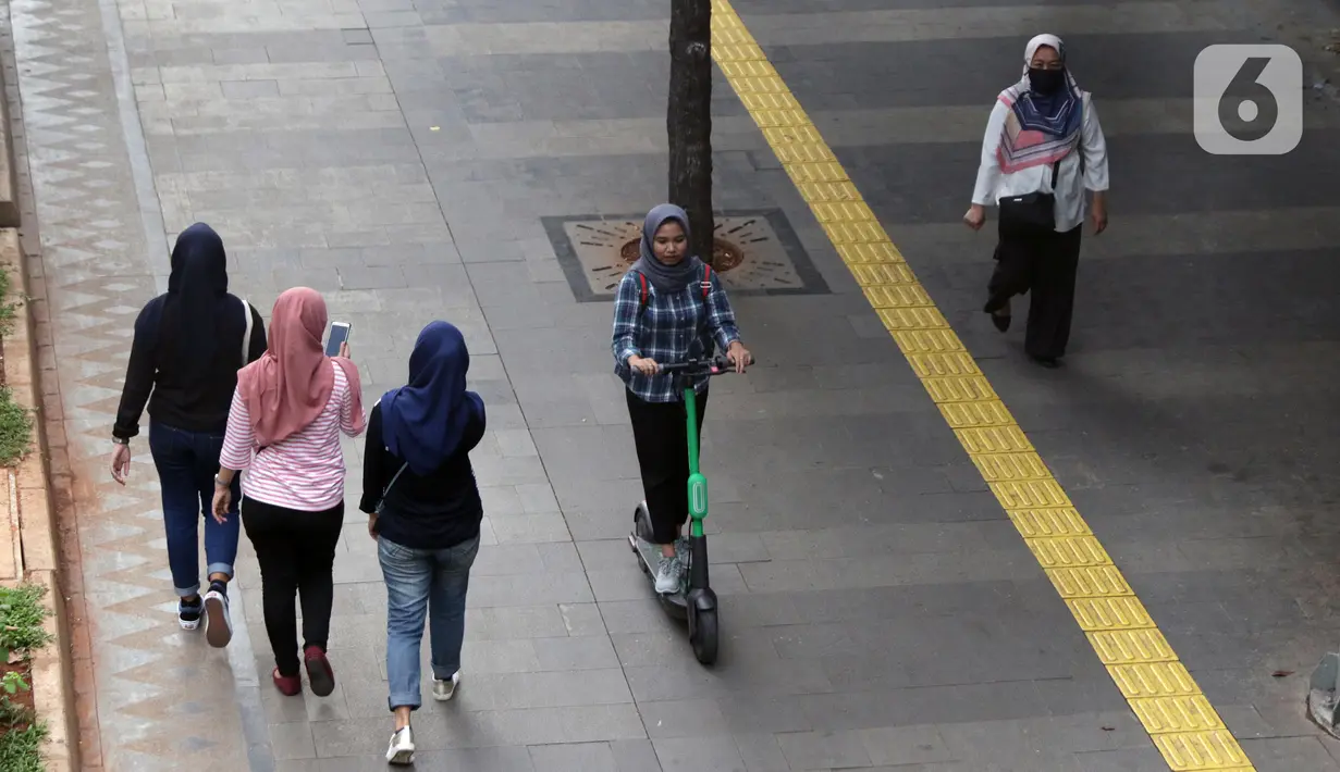 Pengguna otoped listrik Grabwheels melintas di trotoar Jalan Jenderal Sudirman, Jakarta, Kamis (14/11/2019). Pemprov DKI Jakarta melarang penggunaan otoped listrik di trotoar, Jembatan Penyeberangan Orang (JPO) serta pada pelaksanaan Hari Bebas Kendaraan. (Liputan6.com/Helmi Fithriansyah)
