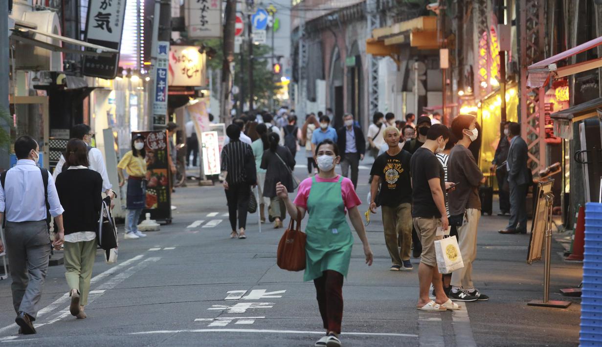 Orang-orang yang memakai masker berjalan di sepanjang jalan selama keadaan darurat di Tokyo, pada Senin (12/7/2021). Otoritas Jepang menempatkan Tokyo di bawah keadaan darurat Covid-19 keempat sebagai upaya menahan lonjakan kasus infeksi Corona dari Senin hingga 22 Agustus. (AP Photo/Koji Sasahara)
