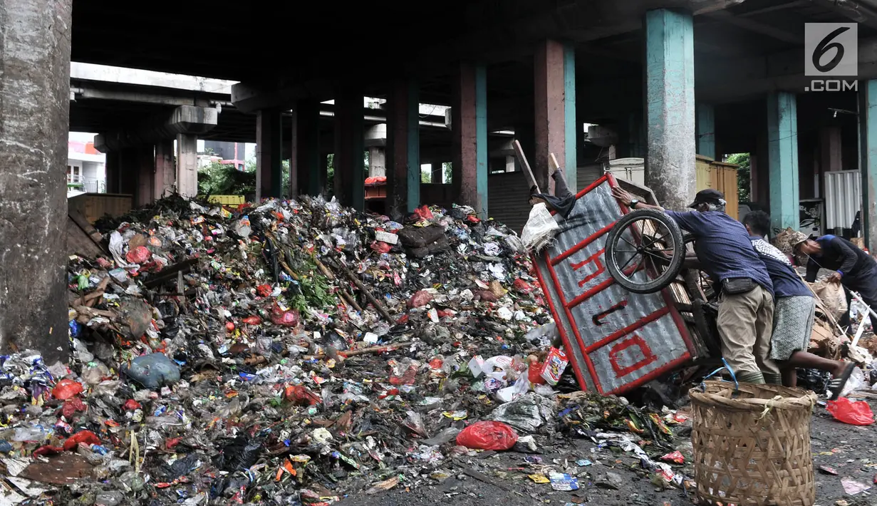 Petugas kebersihan memindahkan sampah dari gerobak ke kolong Tol Wiyoto-Wiyono, Sungai Bambu, Jakarta, Selasa (15/1).  Dalam sehari petugas kebersihan mengangkut sampah hingga 10 truk dengan berat total sekitar 100 ton. (Merdeka.com/Iqbal S. Nugroho)