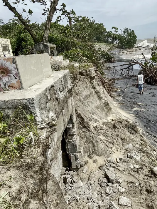Seorang pria berjalan di sepanjang tembok yang rusak akibat topan Batsirai di Mahanoro pada 6 Februari 2022. Topan Batsirai melemah tetapi banjir masih diperkirakan terjadi karena hujan lebat setelah melanda Madagaskar timur dengan angin kencang. (Laure Verneau / AFP)