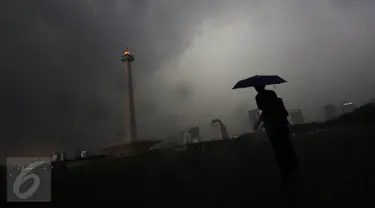 Seorang pegunjung berada di kawasan Monas, Jakarta, Kamis (10/11). Kepala BMKG Andi Eka Sakya menyatakan, cuaca ekstrem yang terjadi di seluruh wilayah Indonesia akan berlangsung hingga Februari 2017. (Liputan6.com/Immanuel Antonius)