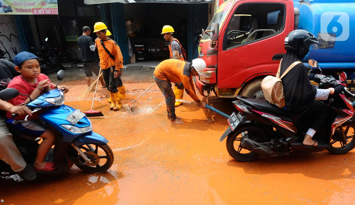 Petugas membersihkan tanah merah berlumpur   di Jalan PLN Raya Gandul  di Kecamatan Cinere, Depok, Jawa Barat, Rabu (31/8/2022). Tanah merah naik dari dalam tanah akibat  proyek pekerjaan Kabel SKTT 150kV Gandul-Kemang,  menyebabkan jalan dipenuhi tanah merah berlumpur. (merdeka.com/Arie Basuki)