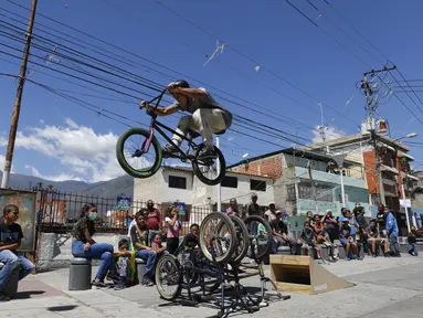 Pebalap BMX Leudar Ruiz melakukan aksi dalam sebuah pertunjukan yang menandai peringatan 400 tahun permukiman kumuh Petare di Caracas, Venezuela (17/2/2021). Petare yang merupakan kawasan kumuh terbesar di Venezuela menjadi rumah bagi lebih dari 500.000 jiwa. (AP Photo/Ariana Cubillos)