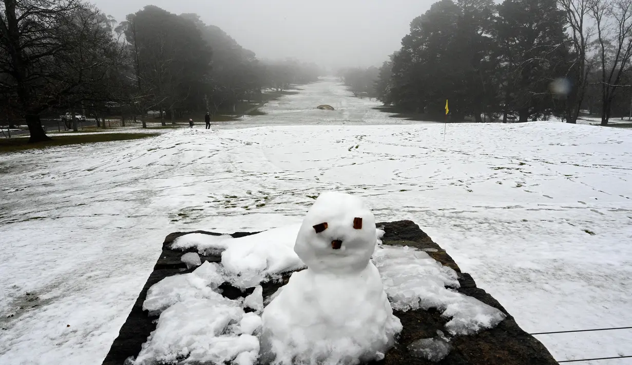 Anak-anak bermain (kiri) di dalam lapangan golf yang tertutup salju pertama musim ini di Katoomba di Blue Mountains (10/6/2021). (AFP/Saeed KHAN)