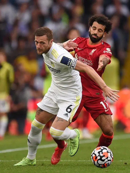 Pemain Leeds United Liam Cooper (kiri) berebut bola dengan pemain Liverpool Mohamed Salah (kanan) pada pertandingan Liga Inggris di Elland Road, Leeds, Inggris, 12 September 2021. Liverpool menang 3-0. (Oli SCARFF/AFP)