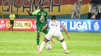 Striker Persebaya, Flavio Silva, mencoba melewati adangan pemain PSIS, Syiha Buddin, pada lanjutan BRI Liga 1 2024/2025 di Stadion Gelora Bung Tomo, Surabaya, Rabu (12/3/2025) malam WIB. (Bola.com/Aditya Wany)