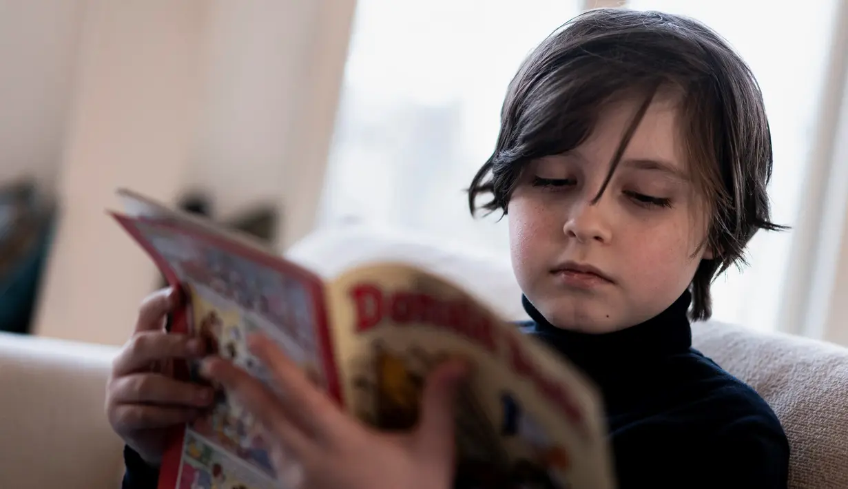 Mahasiswa Belgia Laurent Simons, 9 tahun membaca buku di rumahnya di Amsterdam (21/11/2019). Usai meraih gelar sarjana, Laurent rencananya akan studi ke jenjang yang lebih tinggi. Laurent akan belajar untuk meraih gelar PhD sekaligus mempelajari ilmu kedokteran. (AFP Photo/Kenzo Tribouillard)