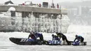 Tim Kepolisian Kota Quebec dilewati oleh Fabien Marceau (belakang) berlomba pada perlombaan kano es Karnaval Musim Dingin Quebec melintasi Sungai St. Lawrence di Kota Quebec, Kanada, 5 Februari 2023. (Jacques Boissinot/The Canadian Press via AP)