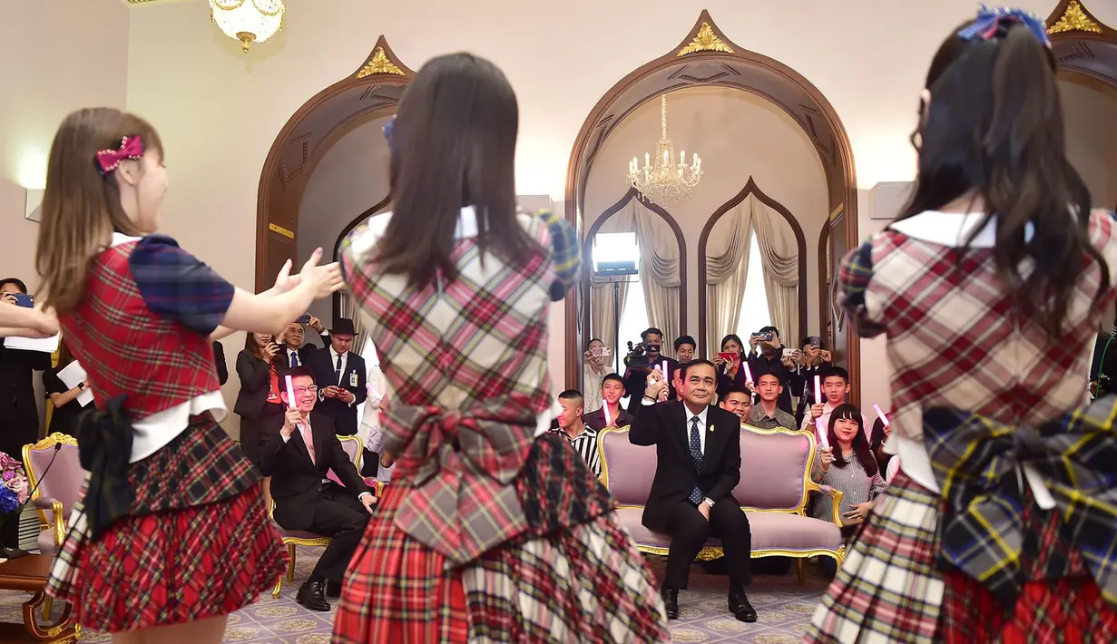Perdana Menteri Thailand, Prayut Chan-O-Cha menyaksikan grup musik Jepang, AKB48, tampil di Gedung Pemerintahan, Kamis (13/8). Kunjungan ini adalah promosi AKB48 untuk mempersiapkan konser di Bangkok pada Desember mendatang. (HO/ROYAL THAI GOVERNMENT/AFP)