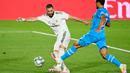 Striker Real Madrid, Karim Benzema, berebut bola dengan gelandang Valencia, Francis Coquelin, pada laga lanjutan La Liga Spanyol pekan ke-29 di Stadion Alfredo, Stefano, Jumat  (19/6/2020) dini hari WIB. Real Madrid menang 3-0 atas Valencia. (AFP/Javier Soriano)