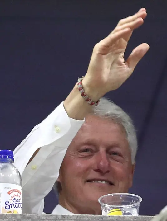 Mantan presiden AS, Bill Clinton melambaikan tangan saat menonton pertandingan antara Roger Federer dan John Millman di AS Terbuka 2018, New York, Senin (3/9). (ALEX PANTLING/GETTY IMAGES NORTH AMERICA/AFP)
