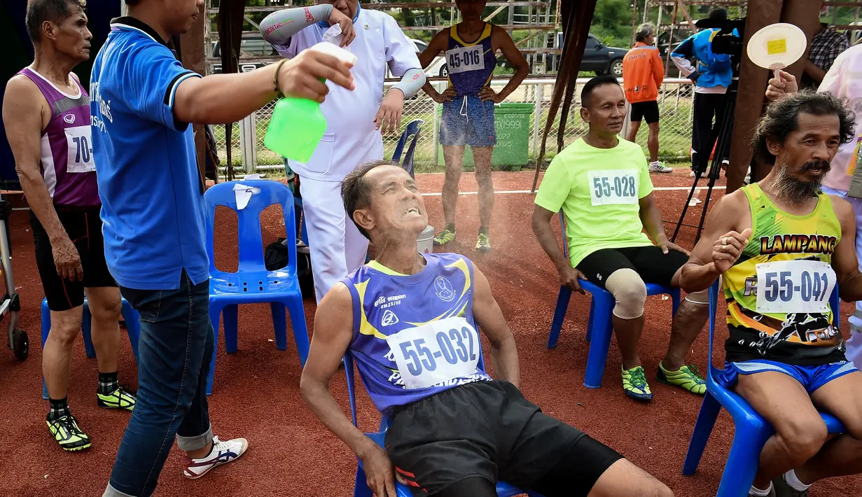 Seorang relawan menyemprotkan air kepada peserta lari lansia 400 meter dalam Elderly Games Nasional di Thailand (25/4). Pertandingan yang diikuti antar lansia ini merupakan yang pertama di Thailand. (AFP/Lillian Suwanrumpha)