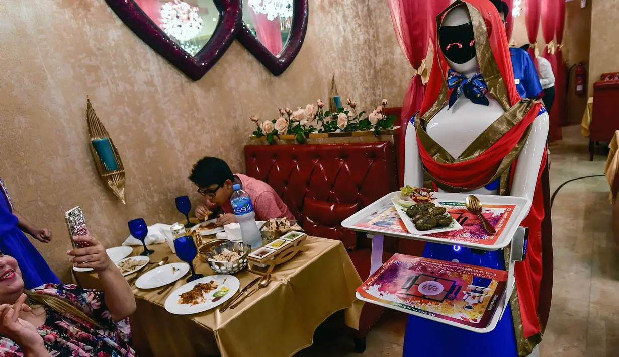 Pengunjung mengambil gambar pelayan robot bernama Ruby yang sedang mengantar makanan kepada pelanggan di restoran Drink and Spice Magic, Dubai, 26 Juli 2018. Robot Jepang itu bekerja tanpa henti dari jam 7 pagi hingga jam 2 pagi. (AFP/GIUSEPPE CACACE)