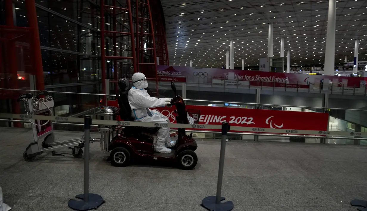 Seorang pekerja Olimpiade dengan pakaian pelindung memasuki bandara Internasional Ibu Kota Beijing setelah Olimpiade Musim Dingin 2022, di Beijing, China, Senin (21/2/2022). (AP Photo/Natacha Pisarenko)