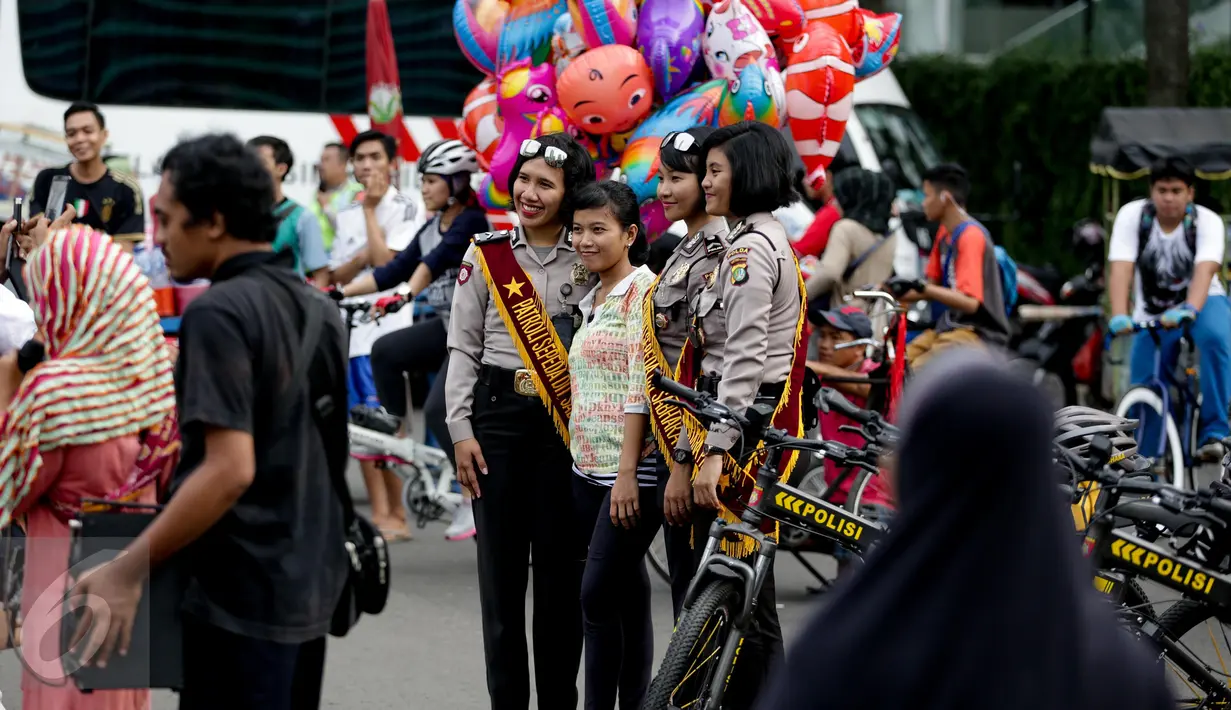 Warga berfoto dengan polisi wanita (Polwan) dari kesatuan Samapta Bhayangkara (Sabhara) Polda Metro Jaya di kawasan Bundaran HI, Jakarta, Minggu (26/3). Polwan bersepeda ini memantau kelancaran car free day. (Liputan6.com/Faizal Fanani)
